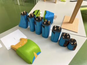 Houten blokken in blauw en groen op een tafel, met stokjes die uit de bovenkant steken.