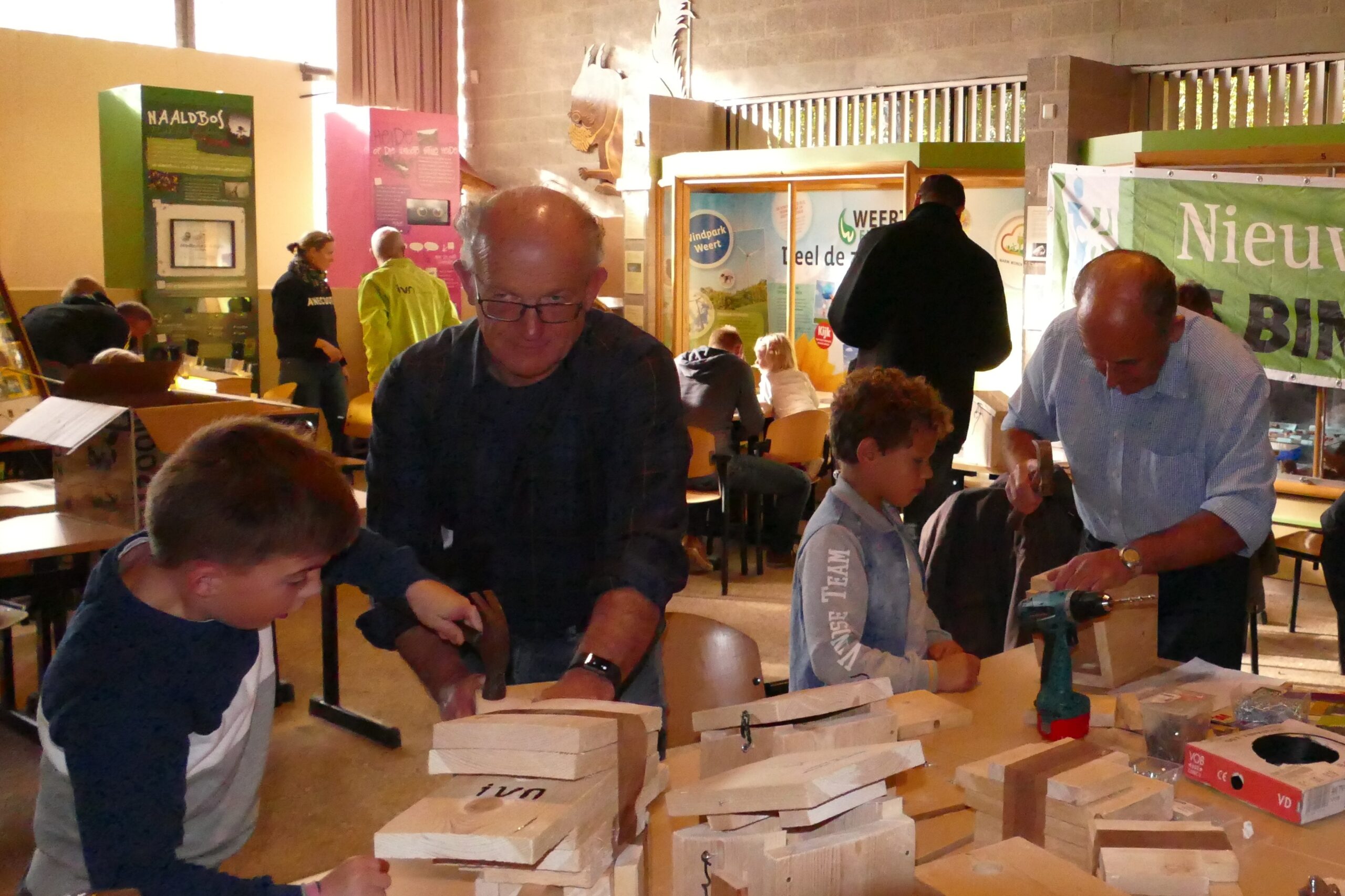 Kinderen bouwen vogelhuisjes met volwassenen in een educatieve workshop.