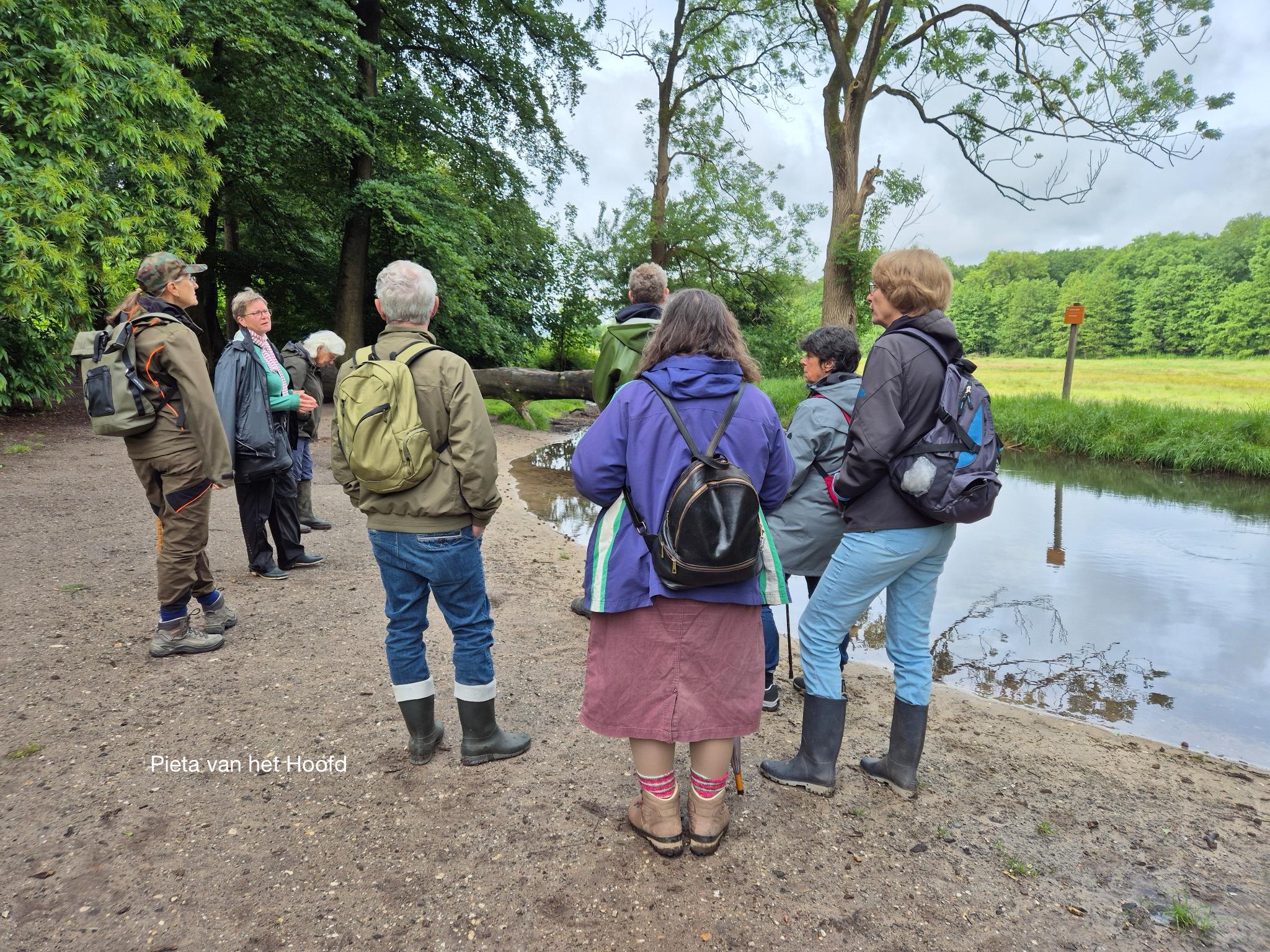 Een groep wandelaars bij een rivier in een bosrijke omgeving.