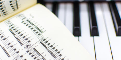 Bladmuziek opengeslagen op een piano klavier, detail van noten en toetsen.