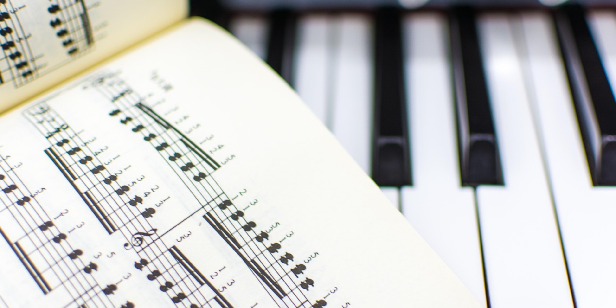 Bladmuziek opengeslagen op een piano klavier, detail van noten en toetsen.