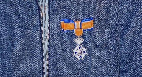 Oranje lint met koninklijk kruis op een blauwe jas.