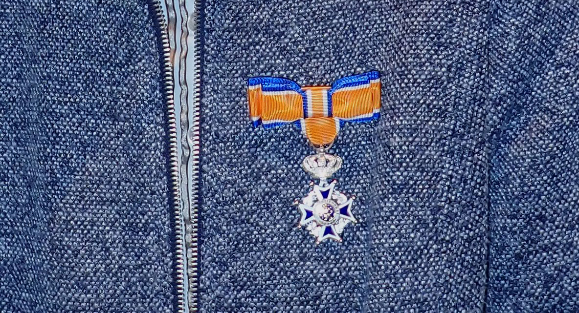 Oranje lint met koninklijk kruis op een blauwe jas.