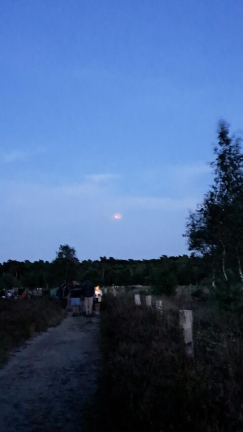 foto met open landschap waar de maansverduistering te zien is, net niet meer volledig
