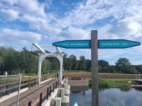 Brug over water met bewegwijzering naar Billerbeck en IJsselmonding. Bosrijke omgeving.