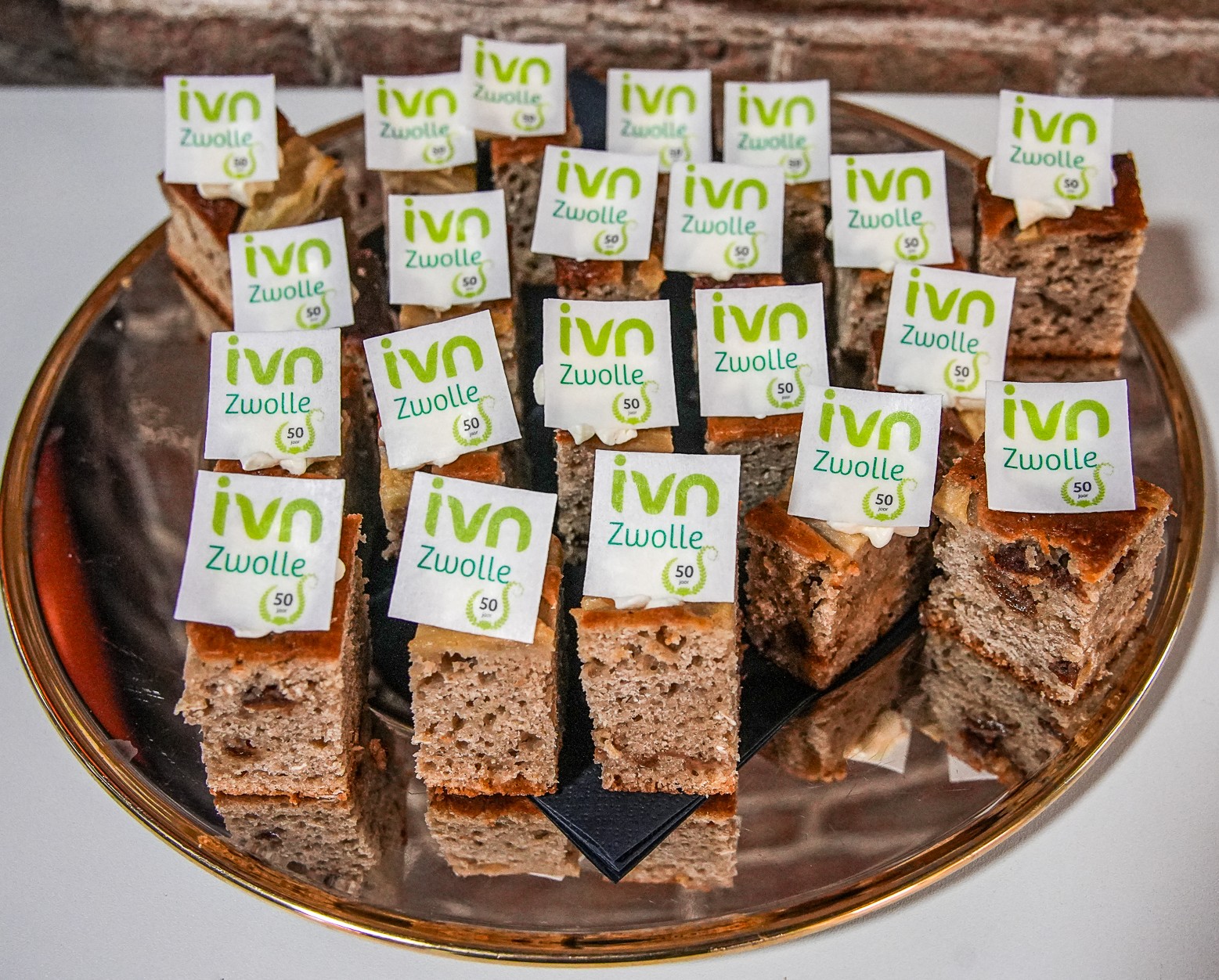 Blokjes cake met labels "ivn Zwolle" op een schaal, ter viering van een 50-jarig jubileum.