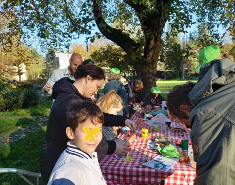 Een groep mensen knutselt aan een tafel in een zonnige tuin.