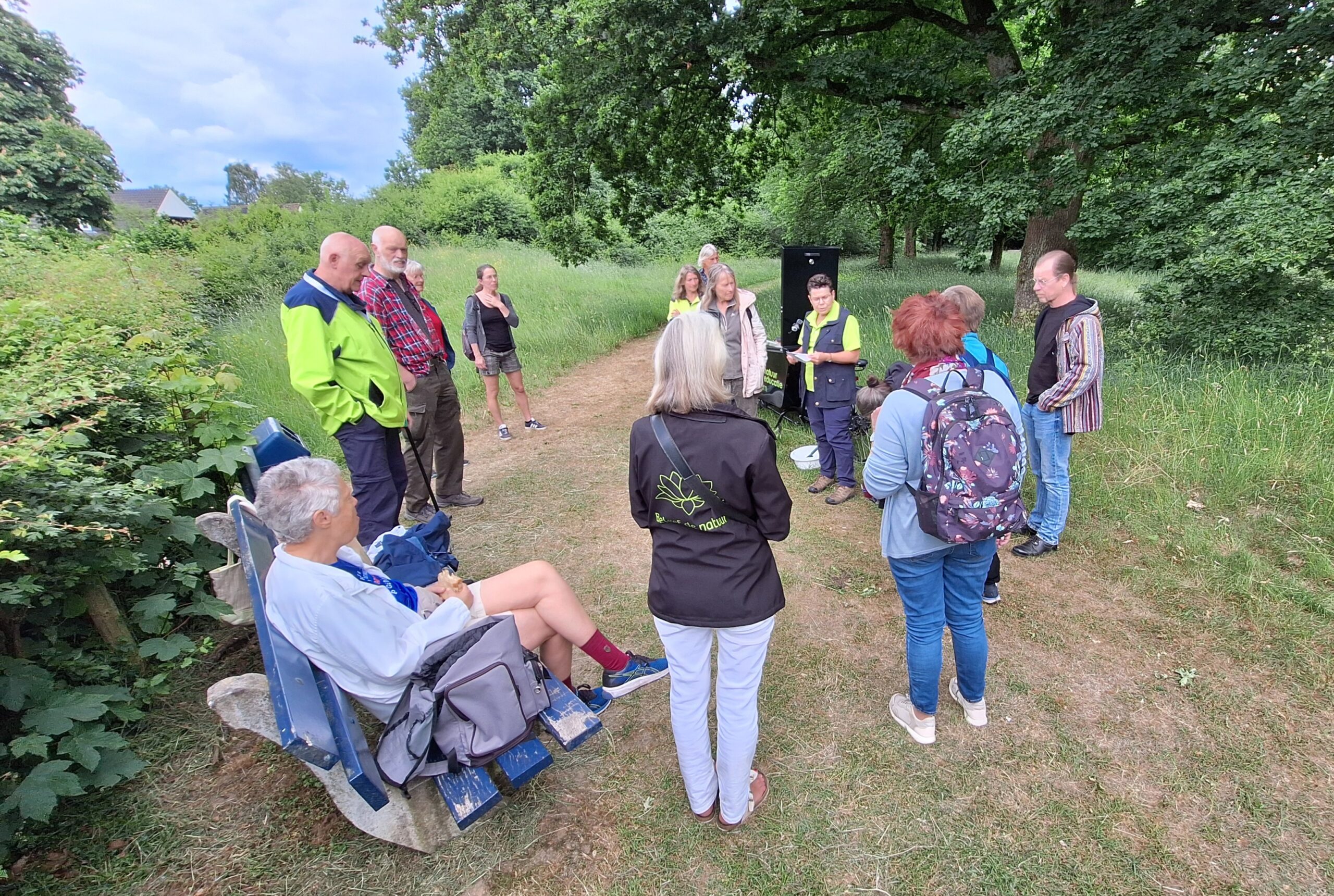 Een groep mensen verzameld in een groene omgeving voor een presentatie.