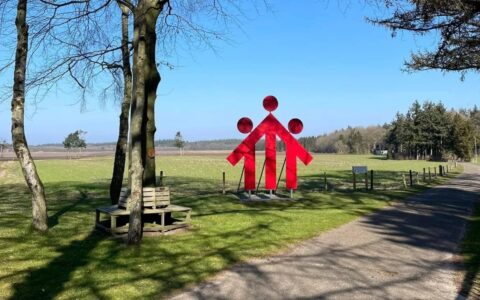 Rood beeld van een gezin in een groen park, met bomen en een pad ernaast.