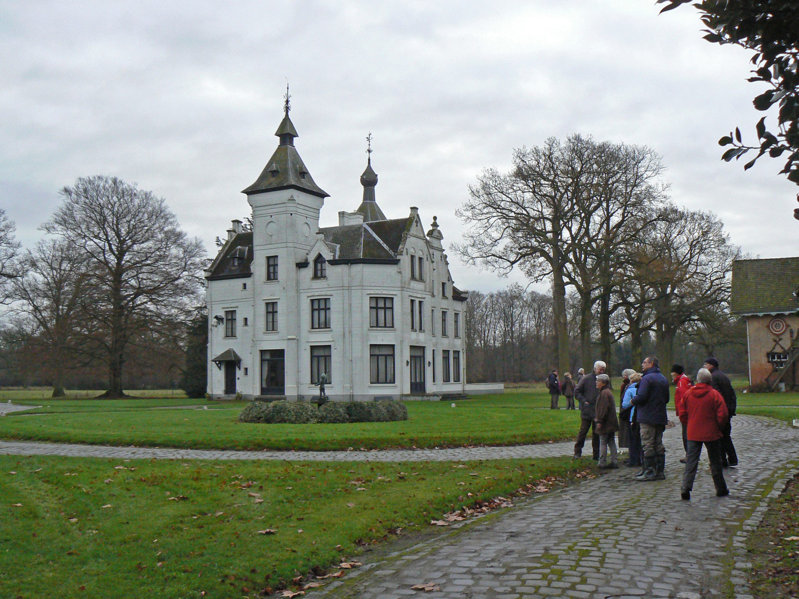 Deelnemers aan de wandeling bekijken het witte landhuis op Wouwse Plantage