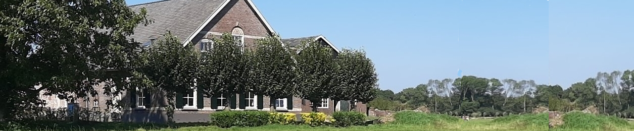 Bakstenen huis met bomen ervoor, omgeven door grasveld en bos onder een blauwe hemel.