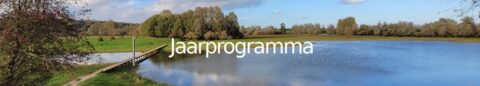Brug over vijver in groene omgeving, tekst "Jaarprogramma" in beeld.