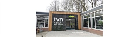 Voorgevel IVN natuureducatiecentrum met houten details en groot logo naast de ingang.