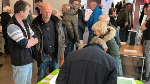 Groep mensen verzameld rond een tafel tijdens een binnenbijeenkomst.