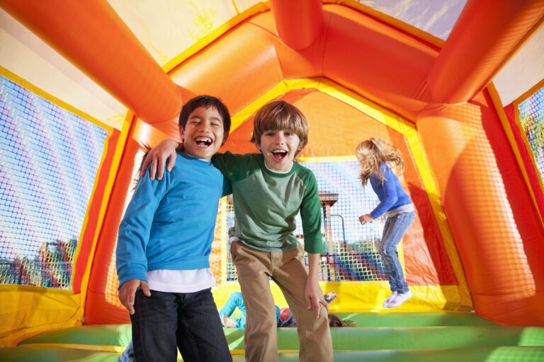 Kinderen springen en lachen in een kleurrijk springkasteel.