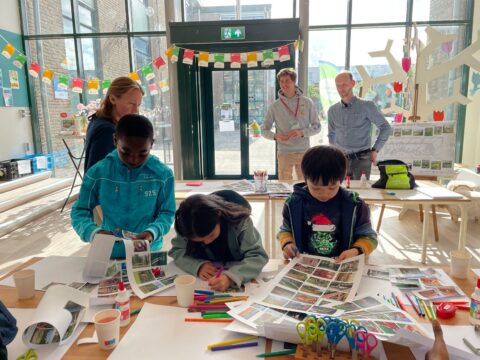 Kinderen knutselen aan tafel met papier en scharen in een lichtgevende ruimte.