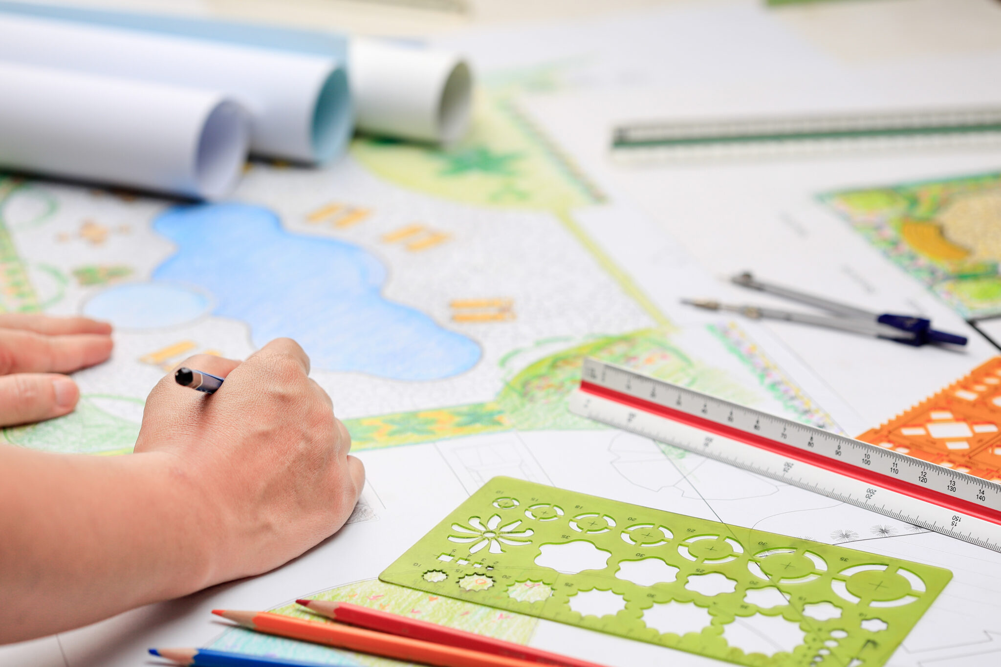 Hand ontwerpen landschapsplan met potloden, liniaal en sjablonen op tafel.