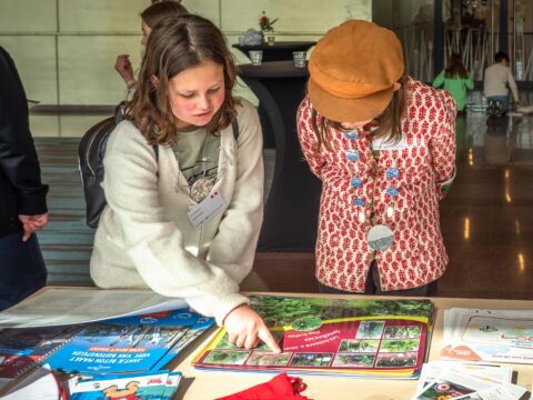Twee kinderen bestuderen informatiefolders op een tafel tijdens een educatief evenement.