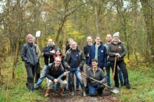 Groep mensen met schoppen in een bosrijke omgeving, mogelijk bezig met een natuurproject.