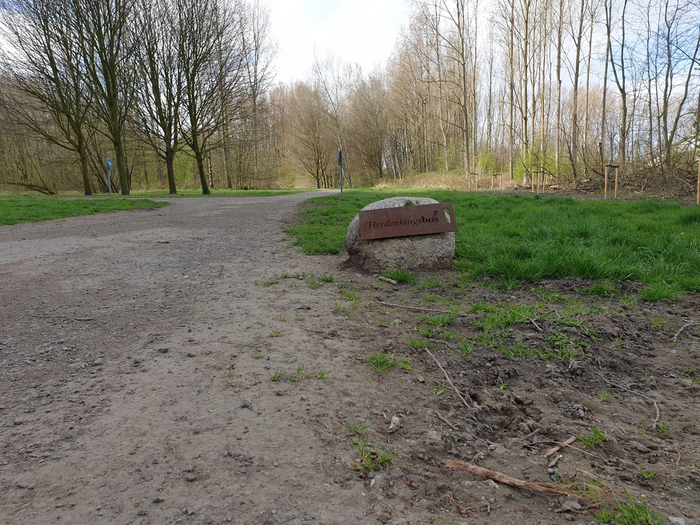 Bospad bij Herdenkingsbos met bomen en steen met opschrift.