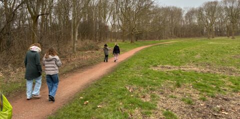 Mensen lopen over een pad in een winterse, boomrijke omgeving.
