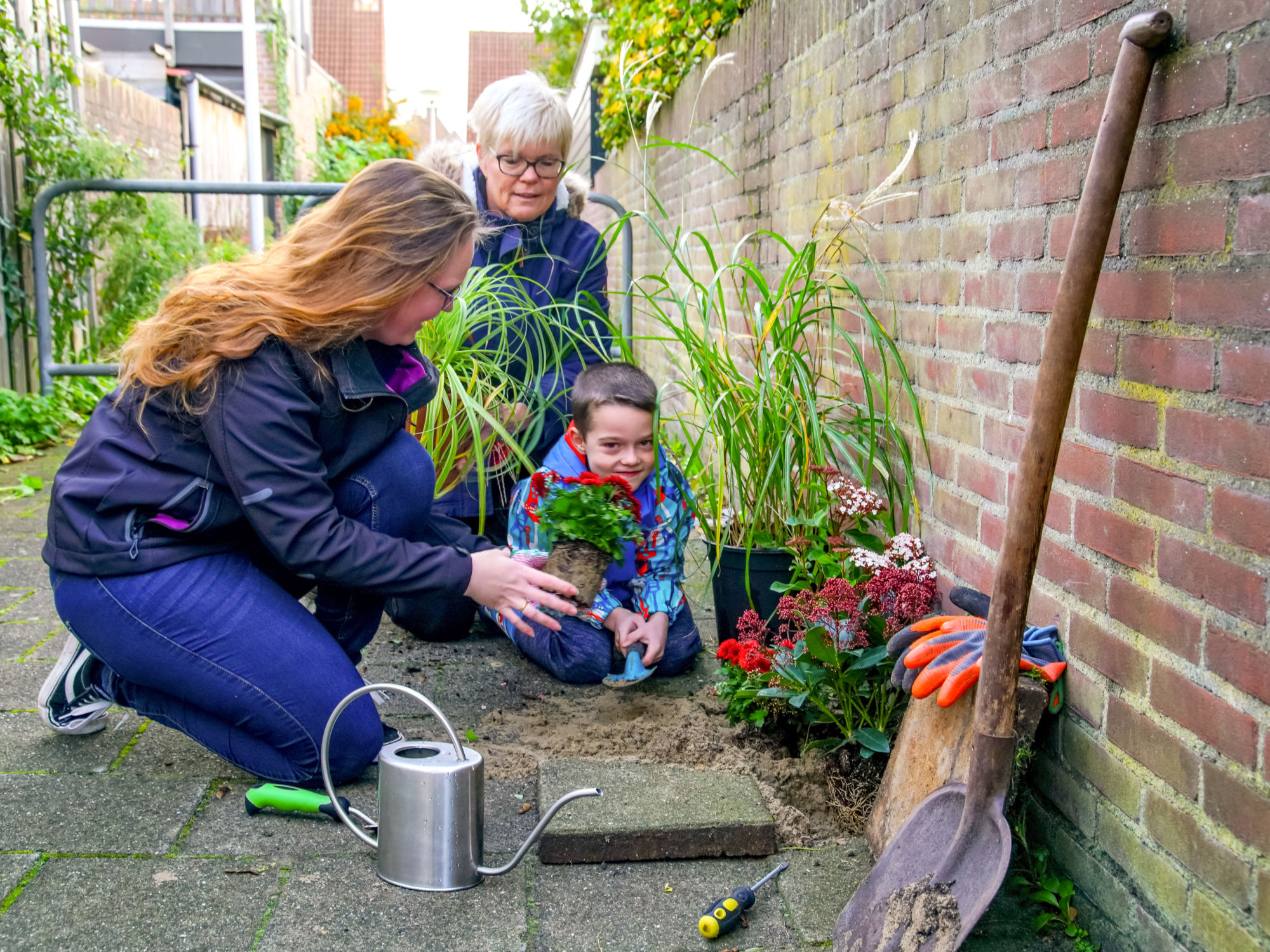 moeder zoon en oma vergroenen tuin, tegel eruit, groen erin