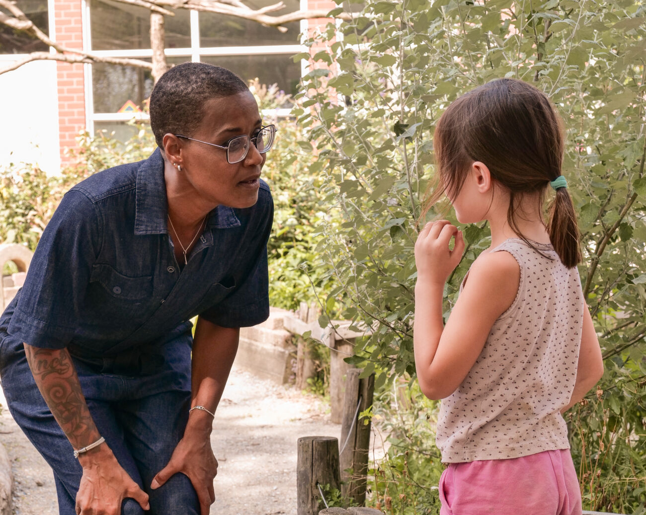 Volwassene en kind in gesprek in een tuin, omringd door groen.