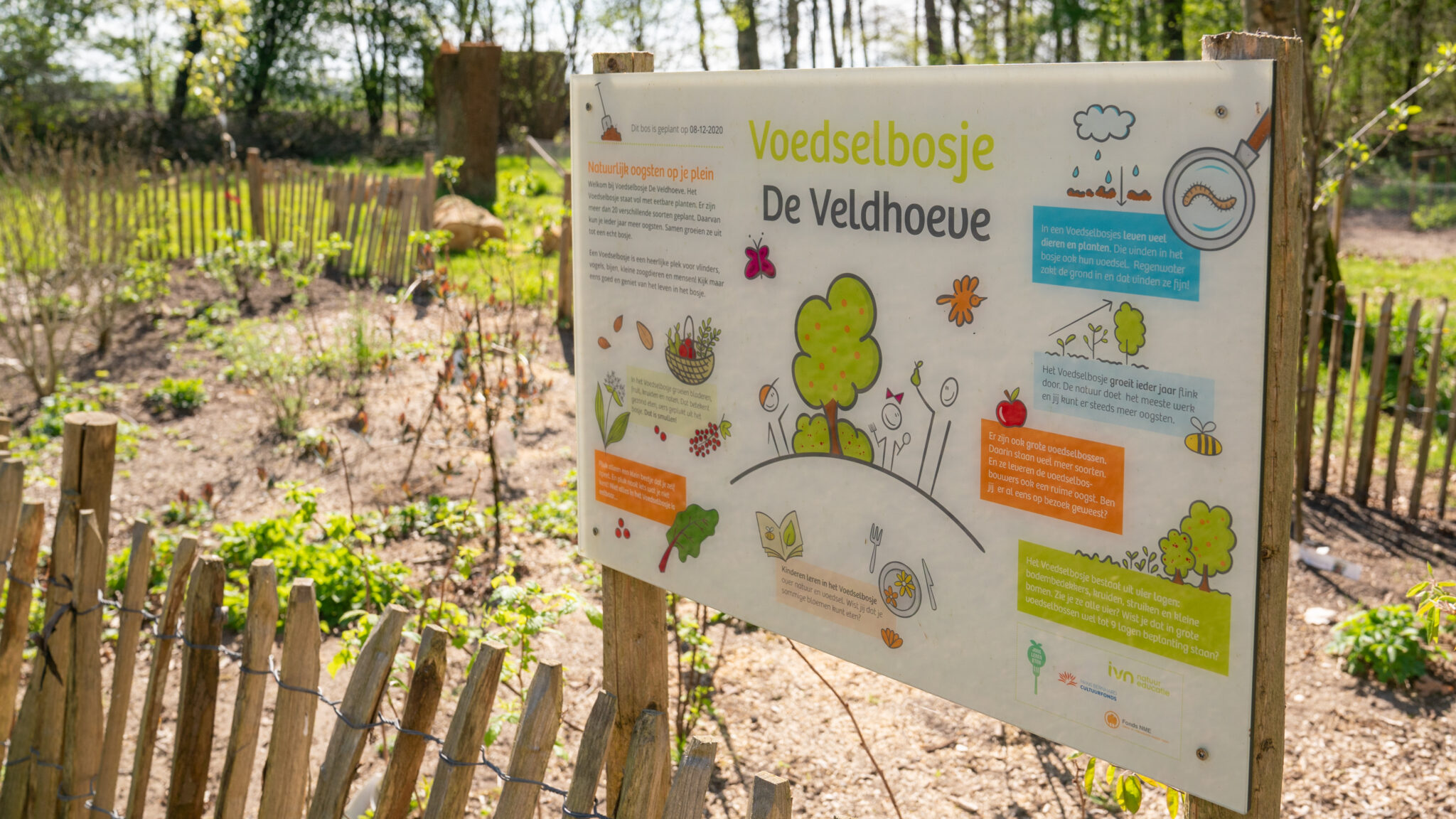 Informeel bord bij Voedselbosje De Veldhoeve, met informatie over biodiversiteit en educatie.