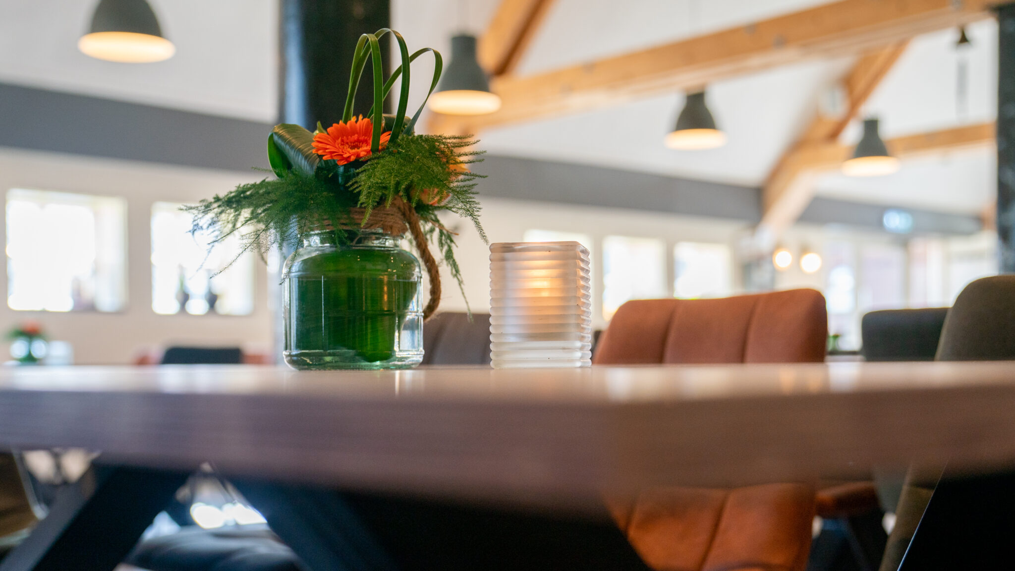 Bloemstuk en kaars op tafel in een modern, sfeervol ingericht café.