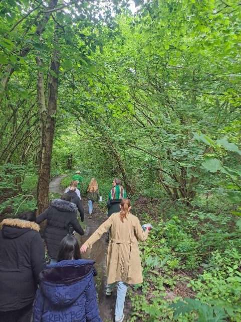 Groep mensen wandelt over een bosachtig pad omgeven door groen gebladerte.