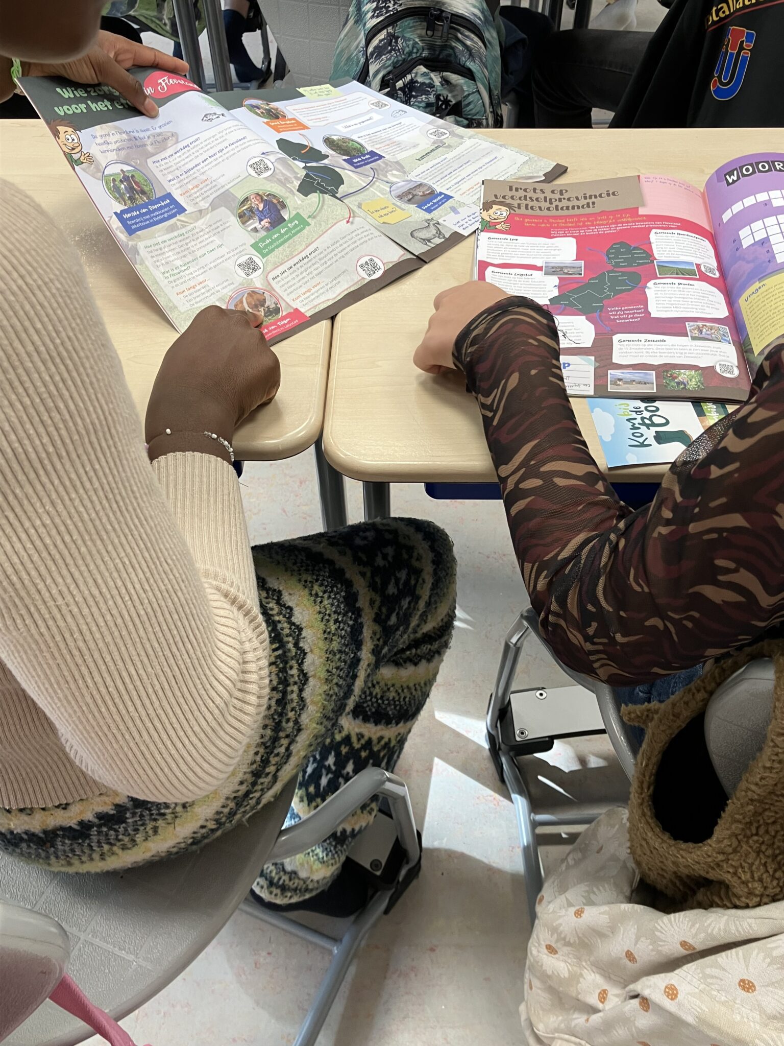 Twee mensen lezen brochures over Flevoland aan een bureautafel.