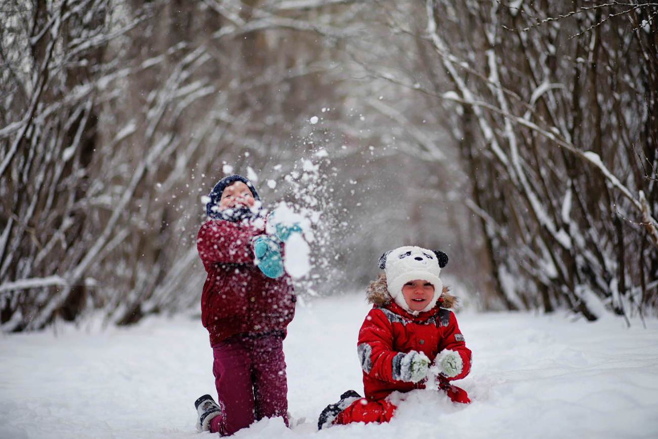 Twee kinderen spelen vrolijk in de sneeuw in een besneeuwd bos.
