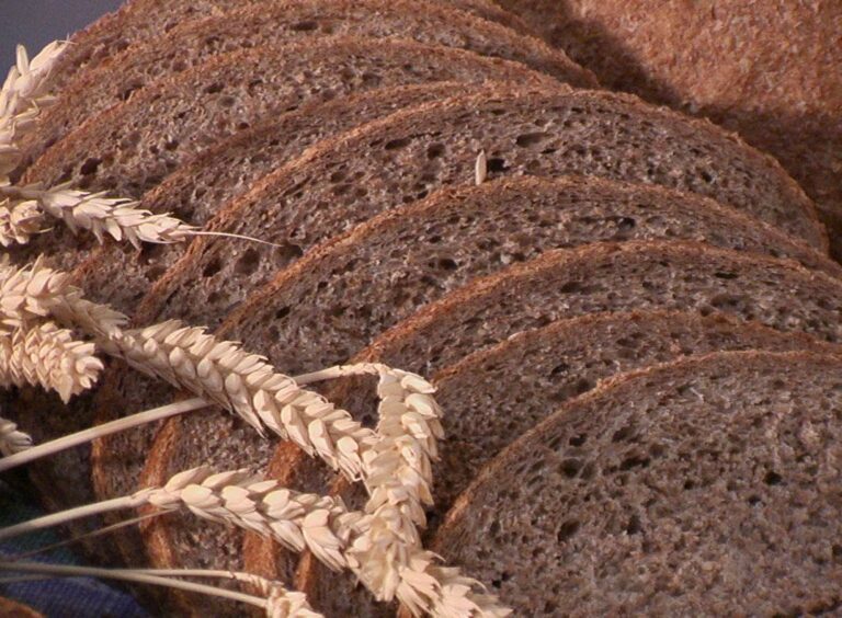 Gesneden volkorenbrood met tarwe-aren op de voorgrond.