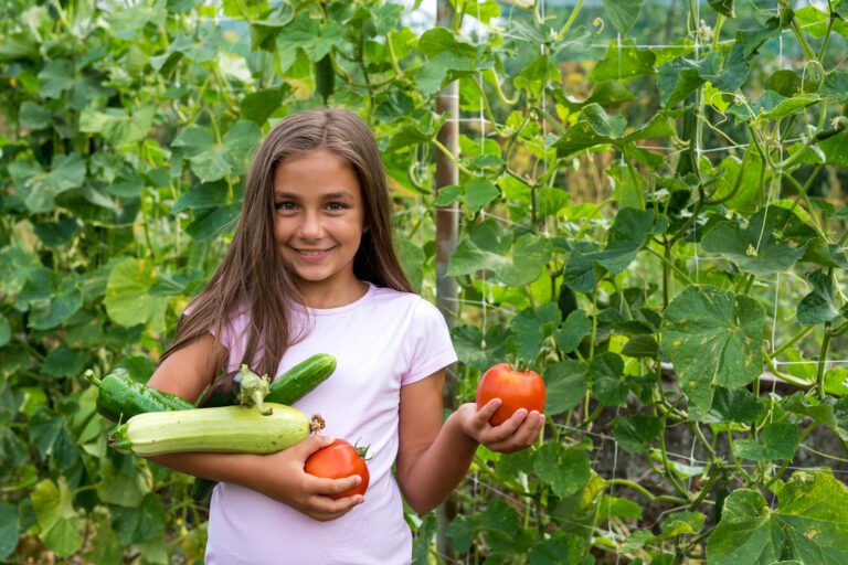 Meisje met groenten, zoals tomaten en courgette, in een groene tuin.
