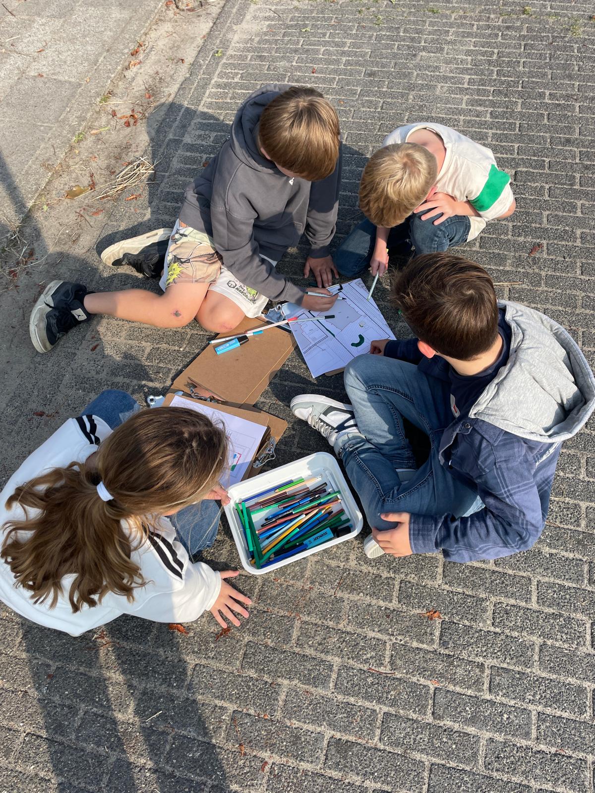 Kinderen zitten op straat en werken samen met pennen en papier.