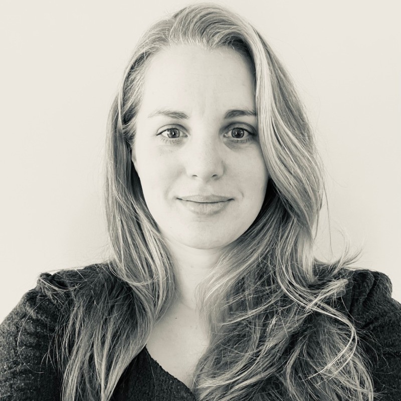 Ik weet niet wie deze persoon is. Zwart-wit portret van een vrouw met lang haar tegen een effen achtergrond.