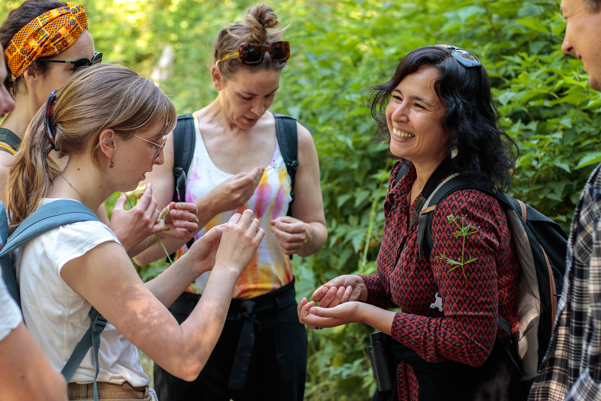 Groep mensen onderzoekt planten en lacht samen tijdens een buitenactiviteit.