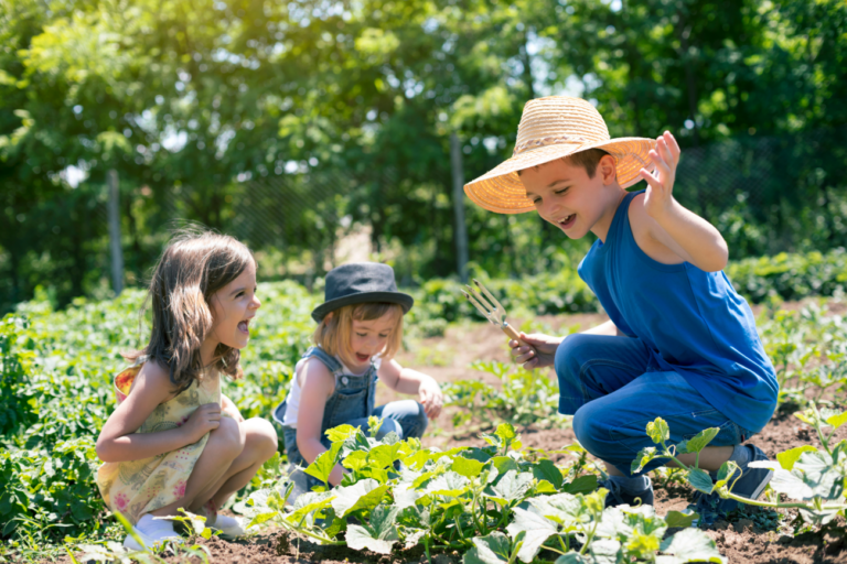 Kinderen tuinen blij in een zonnige moestuin, omringd door groene planten.