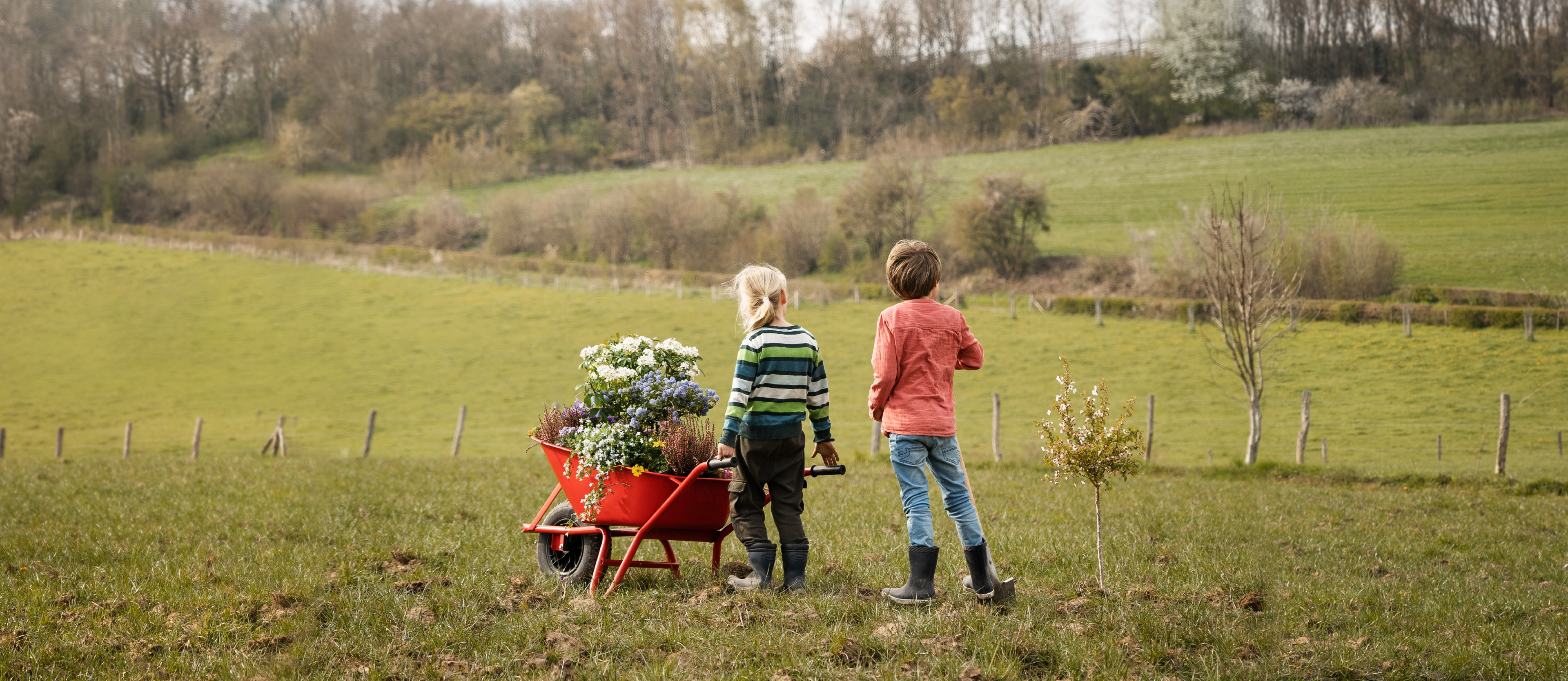 Kinderen in landschap met kruiwagen