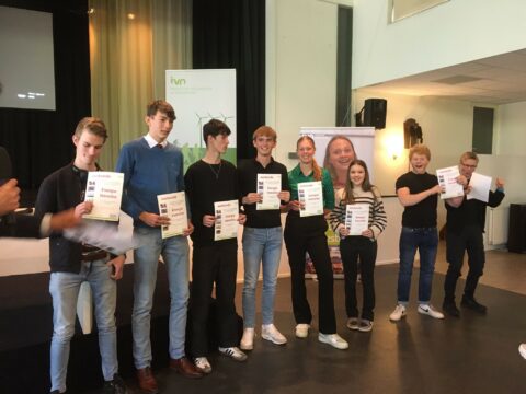 Groep jongeren toont certificaten tijdens een evenement over energietransitie van het IVN.
