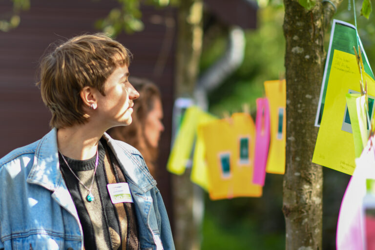 Persoon kijkt naar kleurrijke papieren opgehangen aan een lijn in een buitenomgeving.
