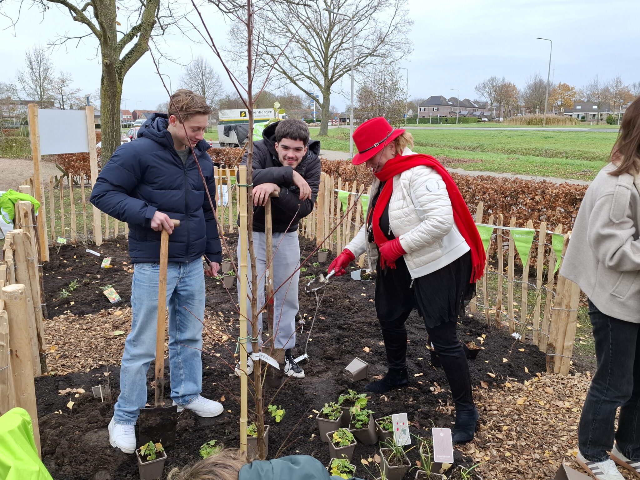 Mensen planten bomen en struiken in een gemeenschappelijk tuinproject.
