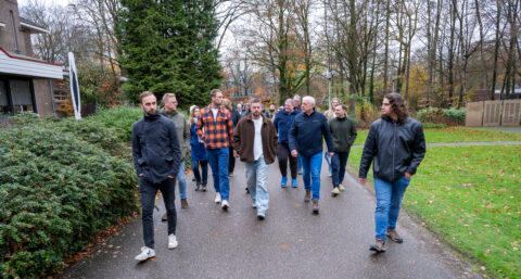 Een groep mensen loopt buiten op een parkpad in een herfstlandschap.