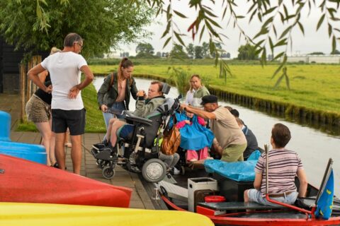 Mensen in een rolstoel worden een bootje in geholpen