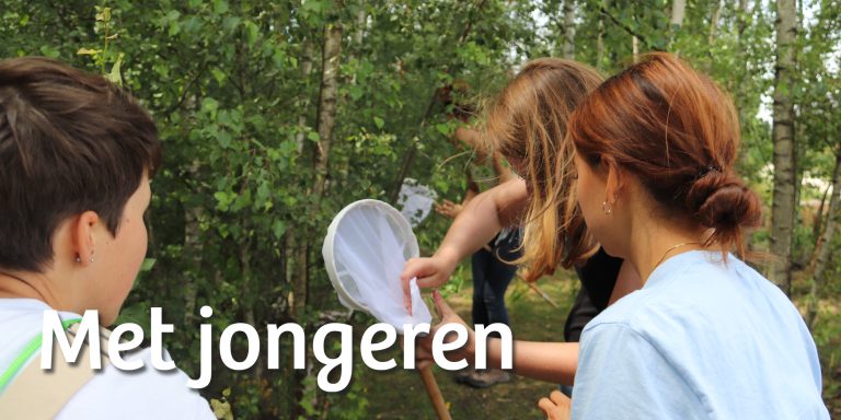 Jongeren met vlindernet bij struik