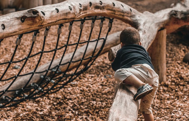 Kind klimt op speeltoestel in groen schoolplein