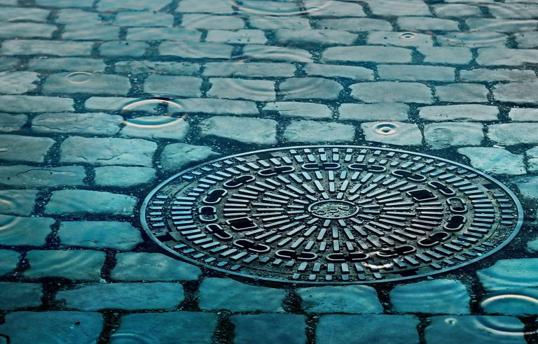 Straat met putdeksel die onder water staat