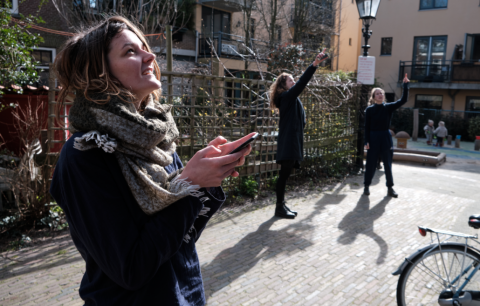 vrouwen wijzen naar gebouw en houden telefoon vast tijdens outside escape