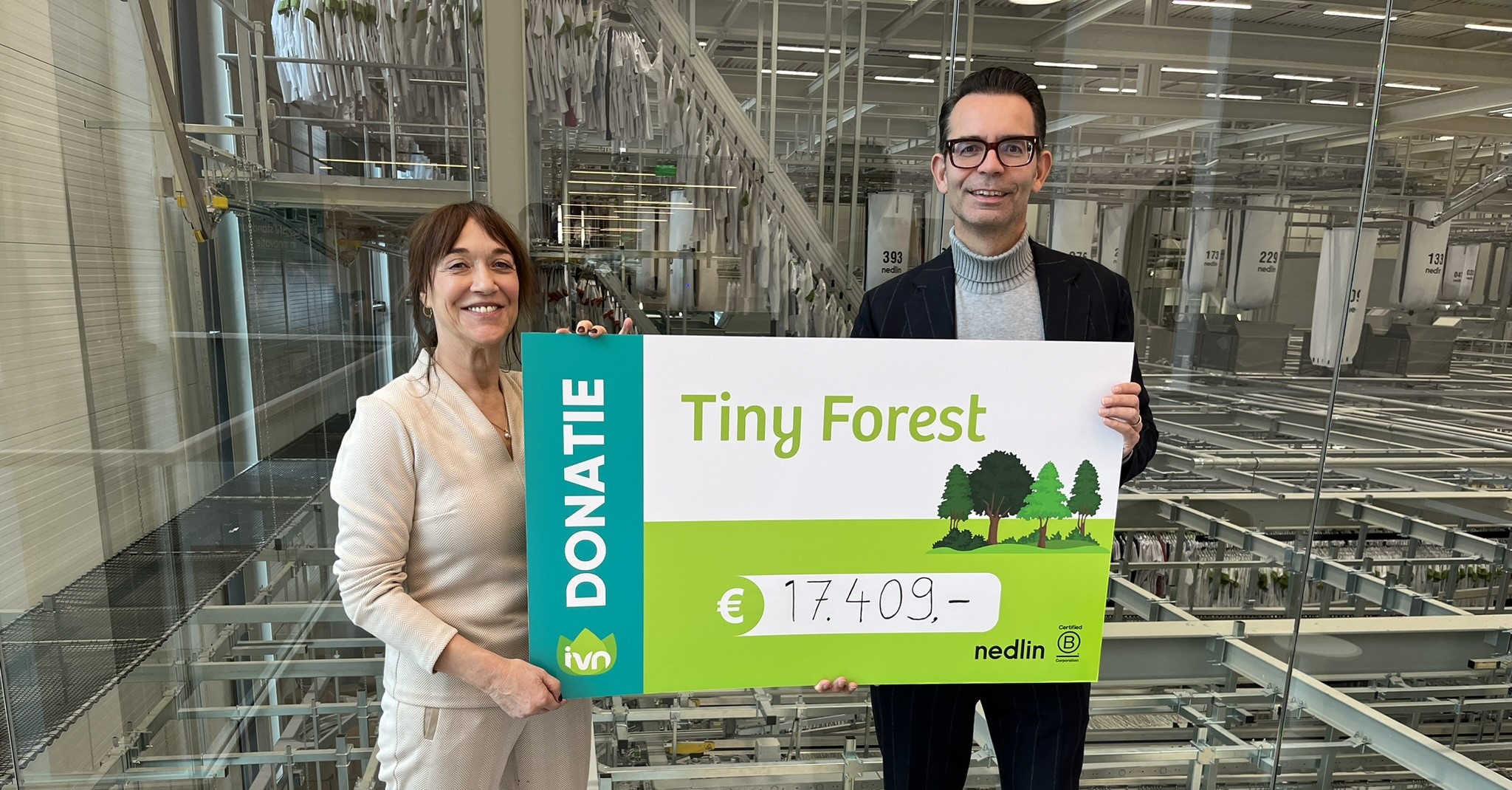 Twee mensen houden een cheque van €17.409 vast voor Tiny Forest donatie.