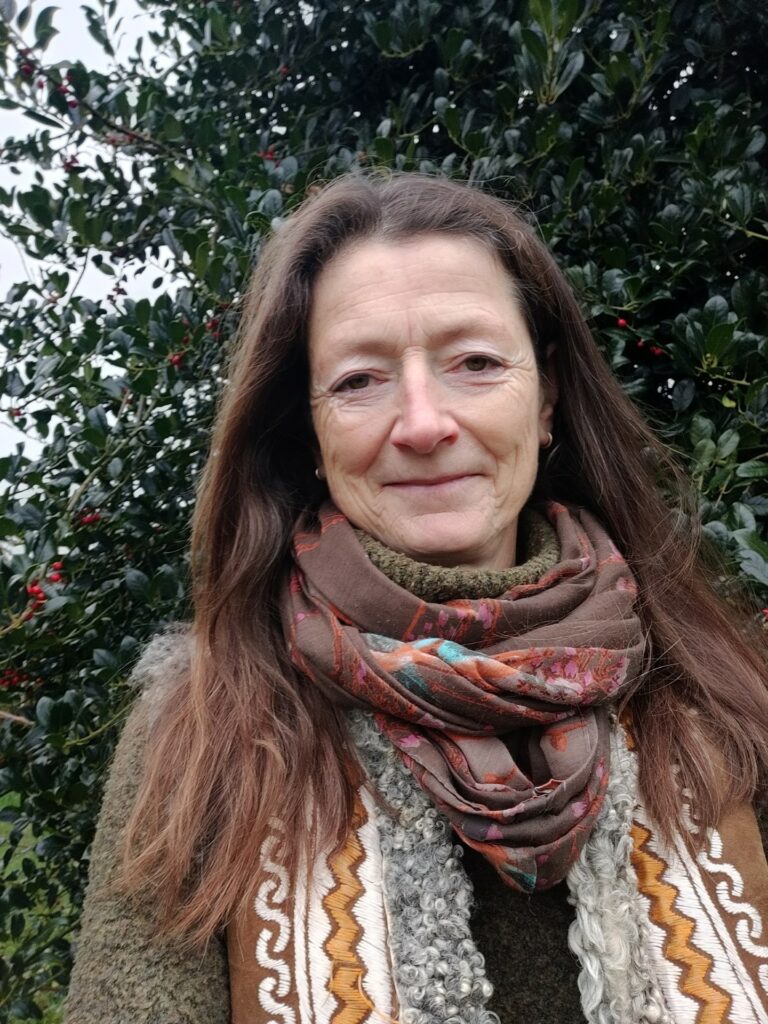 Vrouw met lang haar, sjaal en gebreide kleding voor een hulststruik.